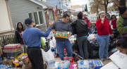 A group of people stand amid cases of bottled water and drinks.